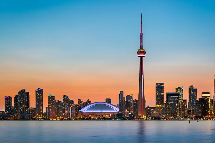 Skyline de Toronto ao anoitecer, com a CN Tower e o Rogers Centre iluminados.