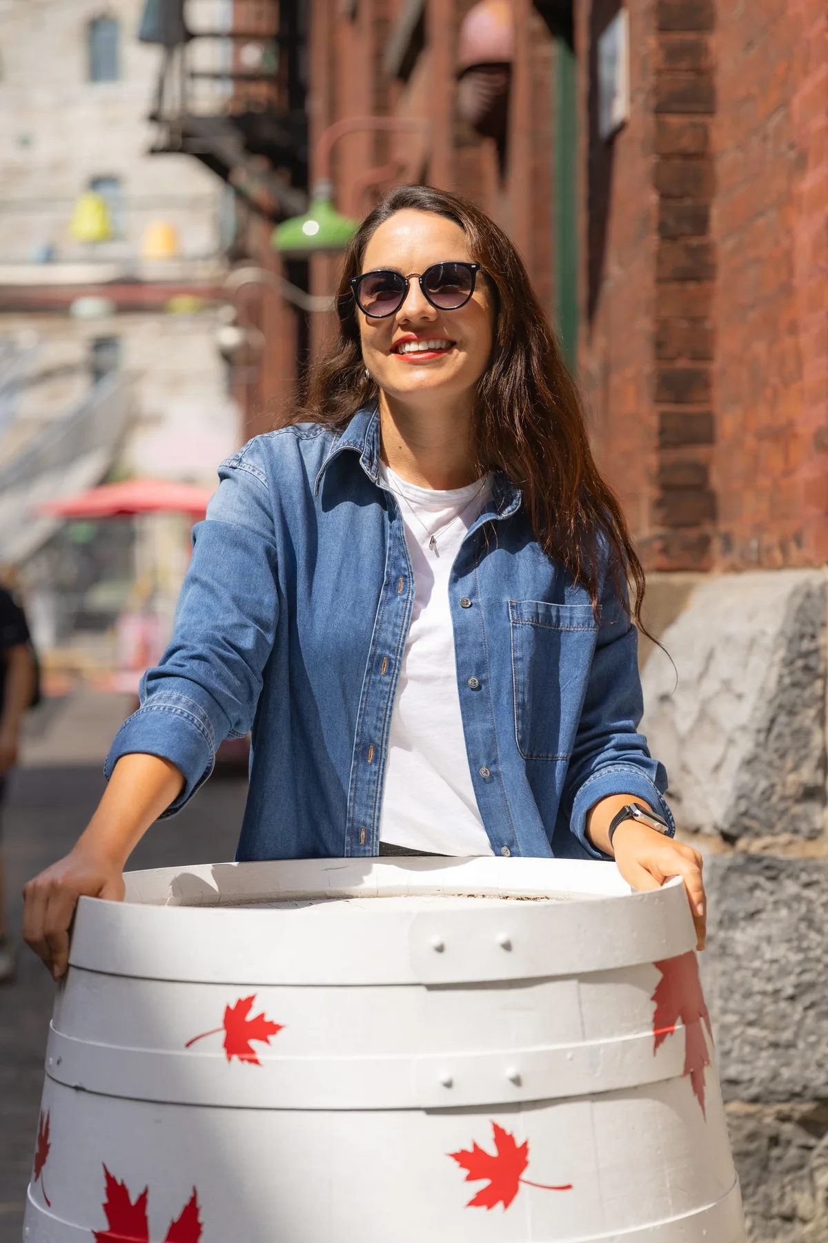 Débora Marques no Distillery District, em Toronto, ao lado de um barril decorado com folhas de bordo.