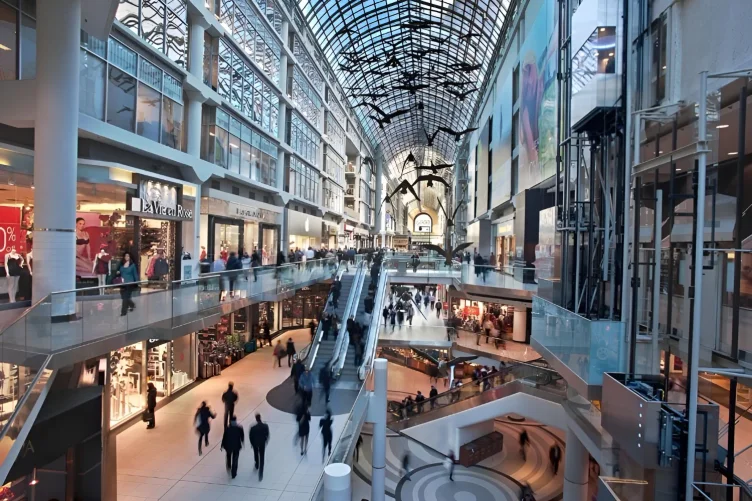 Interior do CF Toronto Eaton Centre com várias lojas e pessoas em movimento.
