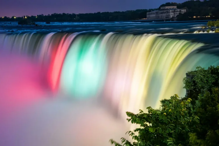 Cataratas do Niágara iluminadas com luzes coloridas durante a noite.