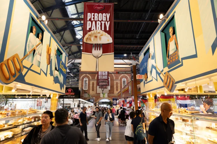 Corredor movimentado do St. Lawrence Market com pessoas e barracas de comidas.