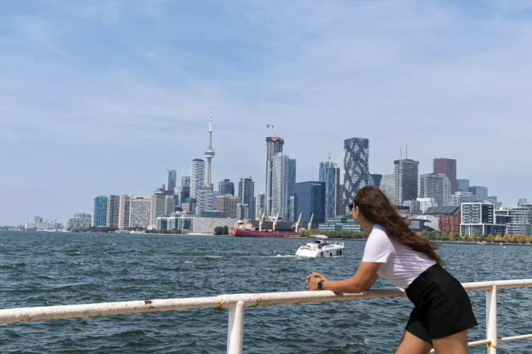 Mulher apreciando o skyline de Toronto do ferry, com a CN Tower em destaque.