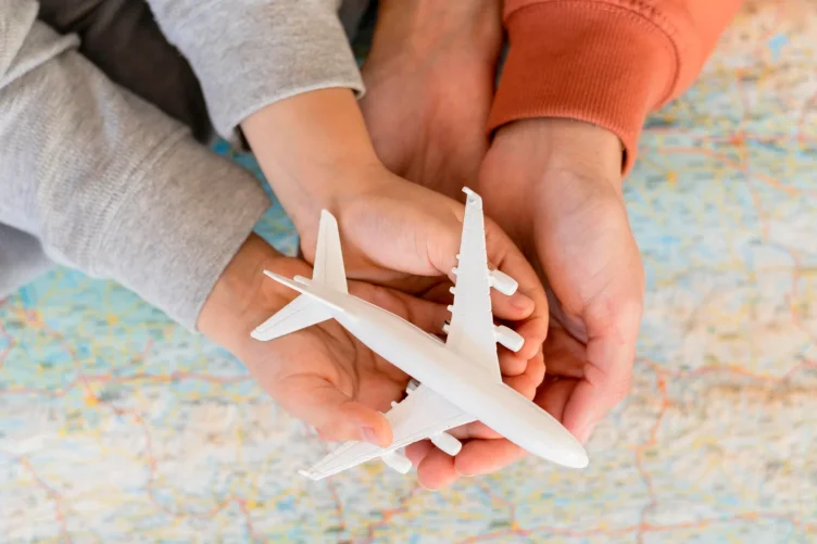 Mãos segurando um avião de brinquedo sobre um mapa, simbolizando planejamento de viagem.