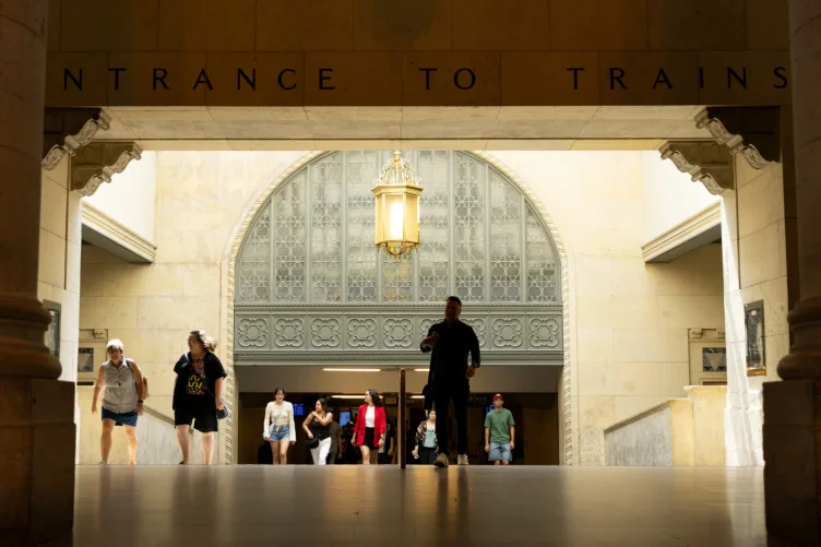 Entrada da Union Station com pessoas caminhando sob uma grande placa “Entrance to Trains”.