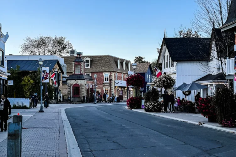 Rua charmosa com casas históricas, bandeiras do Canadá e pessoas caminhando em Unionville.